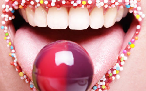 Mund mit Zuckerperlen an den Lippen leckt am Lollipop