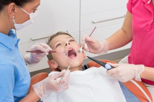 Kind, dass beim Zahnarzt auf dem Behandlungsstuhl sitzt. 