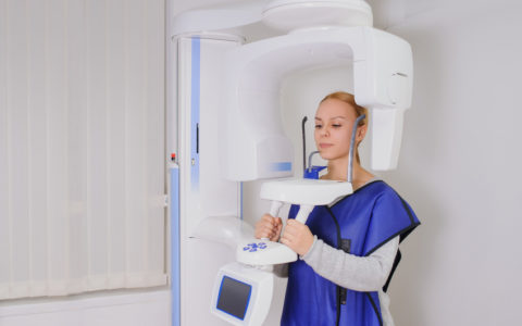Nahaufnahme einer Patientin, die in der Zahnklinik in Schutzkleidung eine Panoramaröntgenaufnahme der Zähne macht. ortopantomography