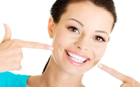 Frau, die ihre perfekten geraden weißen Zähne zeigt.