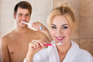 Mann und Frau, die sich die Zähne putzen.