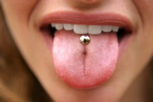 Frau, die ihre Zunge mit Zungenpiercing herausstreckt. 