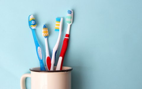 Zahnbürsten in einem Glas auf farbigem Hintergrund. Mundgesundheit, Zähneputzen, gesunde Zähne