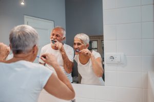 A happy senior couple having fun while brushing teeth on their morning routine.