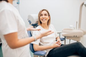 Frau sitzt lächelnd beim Zahnarzt