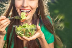 Eine Frau mit weißen Zähnen isst einen Salat