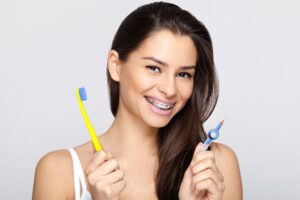 Junge Frau mit Zahnspange und Zahnbürste und Zahnspangenputzer in den Händen