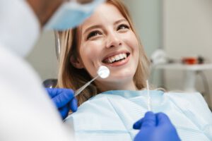 Bild der hübschen Frau sitzt im Zahnarztstuhl, während professionelle Arzt ihre Zähne zu reparieren