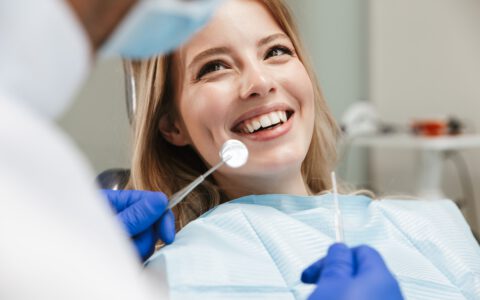 Bild der hübschen Frau sitzt im Zahnarztstuhl, während professionelle Arzt ihre Zähne zu reparieren